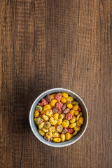Colorful breakfast cereals in the shape of various fruit in bowl on wooden table. Top view.