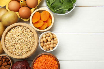 Different products rich in iron on white wooden table, flat lay. Space for text