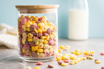 Colorful breakfast cereals in the shape of various fruit in jar on kitchen table.
