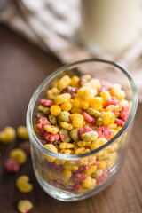 Colorful breakfast cereals in the shape of various fruit in jar on wooden table.