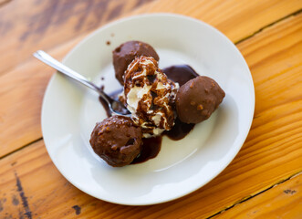Appetizing sweet profiteroles with chocolate topping served for dessert