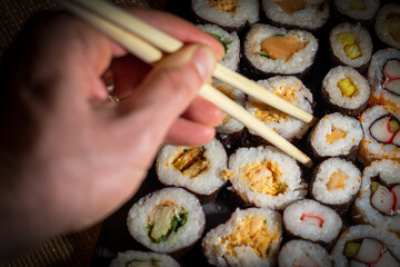 Man hand with bamboo chopsticks taking sushi roll