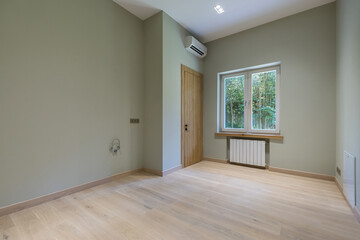 An empty room in a private house with a final finish. Light laminate floor, brown door. .Unfurnished.