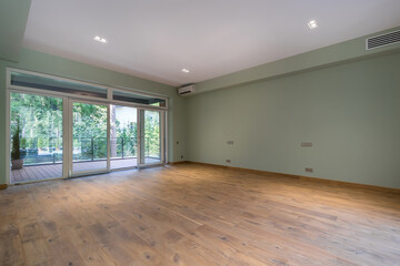 A spacious empty room with the final finish in a private house. Unfurnished. Panoramic .window with glass door. Exit to the terrace.