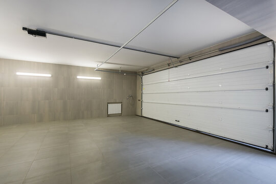 Spacious private garage decorated with light gray tiles. Wide automatic gates.