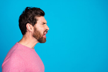 Fototapeta premium Passionate brunet man in casual pink shirt expressing strong emotion against vibrant blue background