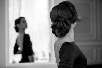 Miss elegance concept. Back of beautiful gracious woman looking at the mirror in a luxury hotel