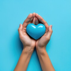 Obraz premium Female hands on a blue background holding a blue heart. The concept of donations and family insurance, World Heart Day. valentine's day.