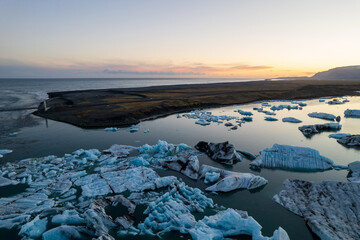 Breathtaking aerial view of Jokulsarlon Glacier Lagoon at sunset, icebergs floating in the serene waters of Iceland most popular tourist destination.