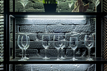 A shelf with wine glasses and a plant on top of it