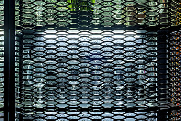 A close up of a metal screen with a plant in the background