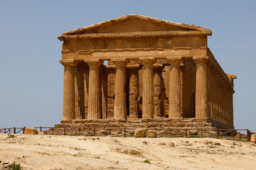 Obraz premium A breathtaking view of Valle dei Templi in Sicily, Italy, featuring ancient Greek temples surrounded by lush greenery and dramatic skies, showcasing the timeless beauty of historical architecture.
