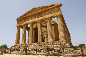 Obraz premium A breathtaking view of Valle dei Templi in Sicily, Italy, featuring ancient Greek temples surrounded by lush greenery and dramatic skies, showcasing the timeless beauty of historical architecture.