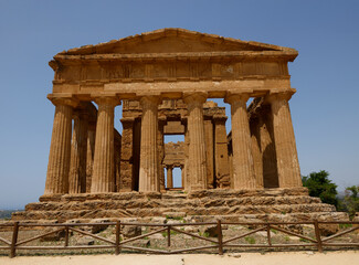 Obraz premium A breathtaking view of Valle dei Templi in Sicily, Italy, featuring ancient Greek temples surrounded by lush greenery and dramatic skies, showcasing the timeless beauty of historical architecture.