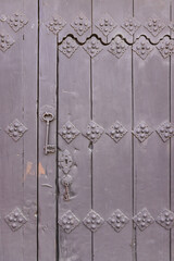 An antique key hanging from an old door.