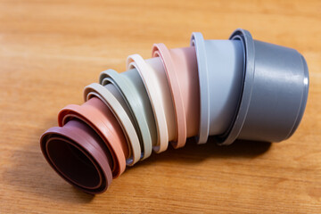 Pastel colored plastic cups from disassembled pyramids scattered on wooden surface, showcasing pieces ready for play and learning