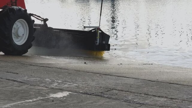 A marina slipway being cleaned with machinery comprising a telehandler and hydraulic rotating brush.