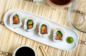 Set of fresh sushi rolls with salmon, avocado and sesame seeds served on plate. Japanese sushi uramaki or California roll.