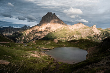 The Midi d’Ossau peak towers over verdant valleys and Ayous Lake in the summer Pyrenees.