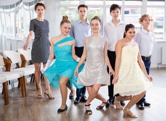 Fototapeta premium Group of students, teen boys and girls, pose with female mentor after ballroom dancing class. Girls curtsy