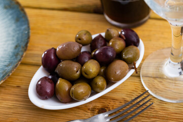 Large black olives and green olives with pits served to table in bowl