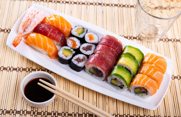 Service plate containing maki, uramaki and nigiri and soy sauce on the laid table in restaurant
