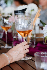 Elegant hand holding a glass of rose wine, surrounded by vibrant table decor at a festive gathering