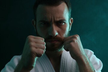 Karate fighter wearing uniform in color lights and smoke, closeup