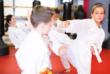 Obraz premium Preteen boy and girl, working in pair, mastering new karate moves in class