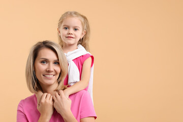 Cute little girl with her mom on beige background, space for text. Happy Mother's Day