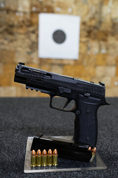 Tactical modern 9mm pistol with slots in the slide in shooting range. Vertical photo.