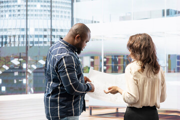 Businesswoman and realtor touring an office space for relocation, evaluating the layout and discussing high class urban property investment. Advising on an office leasing contract.