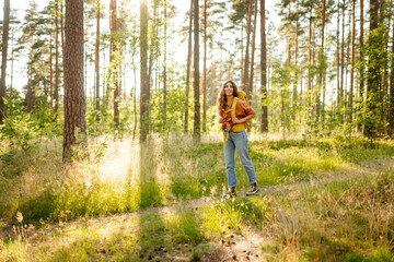 Obraz premium Woman tourist with backpack is relaxing in the fresh air in the forest, feeling happiness and connection with nature.