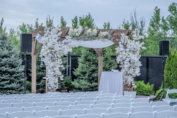 Chuppah Wedding arch is decorated with cloth and flowers outdoors. Beautiful wedding set up. Wedding ceremony Part of the festive decor, floral arrangement.