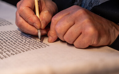 A traditional Jewish Torah scribe "sofer stam" working on a new Torah script A hand writes letters in the Sefer Torah, the holiest book in Judaism