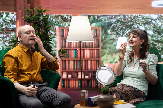 Senior people applying rejuvenating serum and doing daily routine together for skincare, to preserve their aging skin. Couple using moisturizer and UV protection cream on their cheeks. - Powered by Adobe