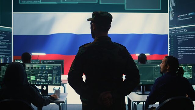 Russian military personnel in high tech government office spreading fake news and hybrid warfare propaganda, making threats. Russian army private stealing classified information from rivals. Camera B.