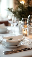 Fototapeta premium Close-up of an elegant dining table setting with white dishes, glasses, and greenery, creating a sophisticated and inviting dining atmosphere