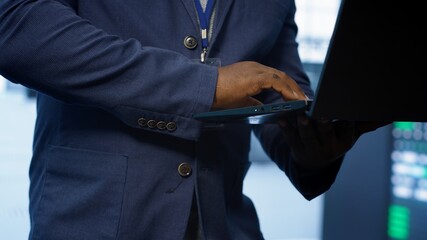 Technician in server hub using laptop to patch network issues leading to slow data transfer rates. Close up of IT professional in data center fixing errors affecting supercomputers, camera A