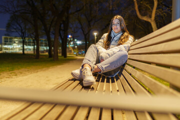 Young woman sitting on the bench at night..