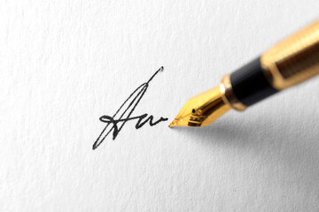 Fountain pen leaving signature on paper, closeup