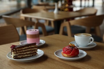 Aromatic coffee and delicious desserts served on wooden table in cafe