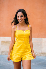 Young woman smiling and walking in a yellow jumpsuit
