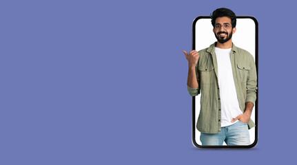 A young man smiles while interacting through a smartphone with a large screen, showcasing the convenience of modern technology for social media and communication.