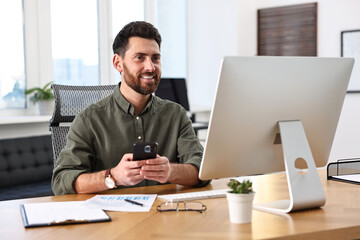 Fototapeta premium Man using smartphone at table in office