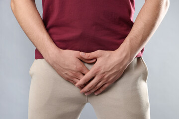 STD (sexually transmitted diseases). Man suffering from symptoms on grey background, closeup
