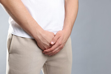 STD (sexually transmitted diseases). Man suffering from symptoms on grey background, closeup