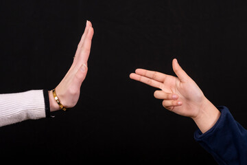 mains montrant un stop face à une main mimant une arme, stop violence © Esta Webster