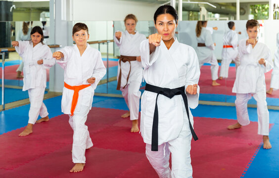 Focused children trying new martial moves in a practice during karate class in gym with their coach
