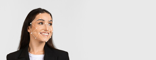 A woman with long hair smiles while facial recognition technology overlays her features. The...